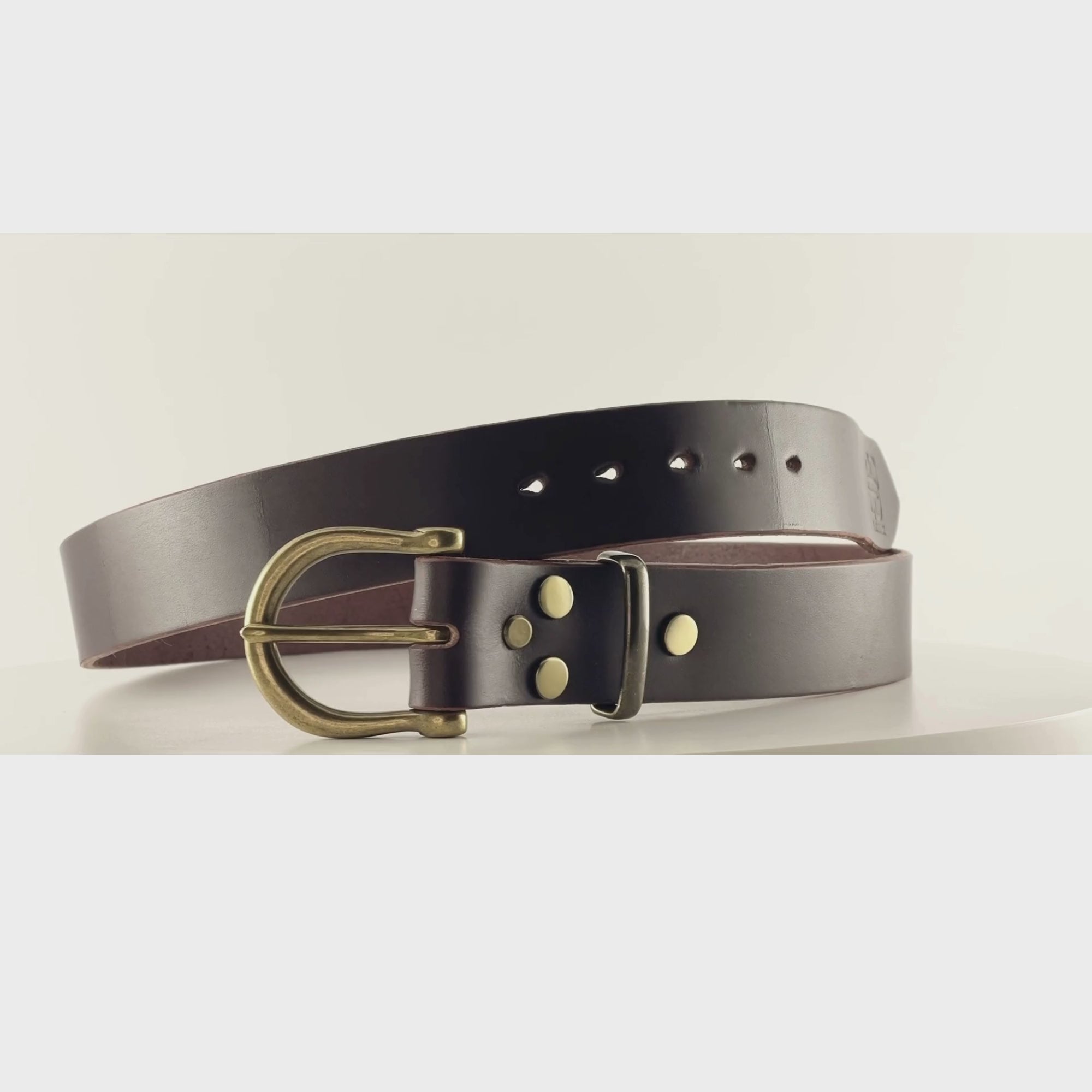 Video of a dark brown belt with a semi-circular brass buckle on a carousel