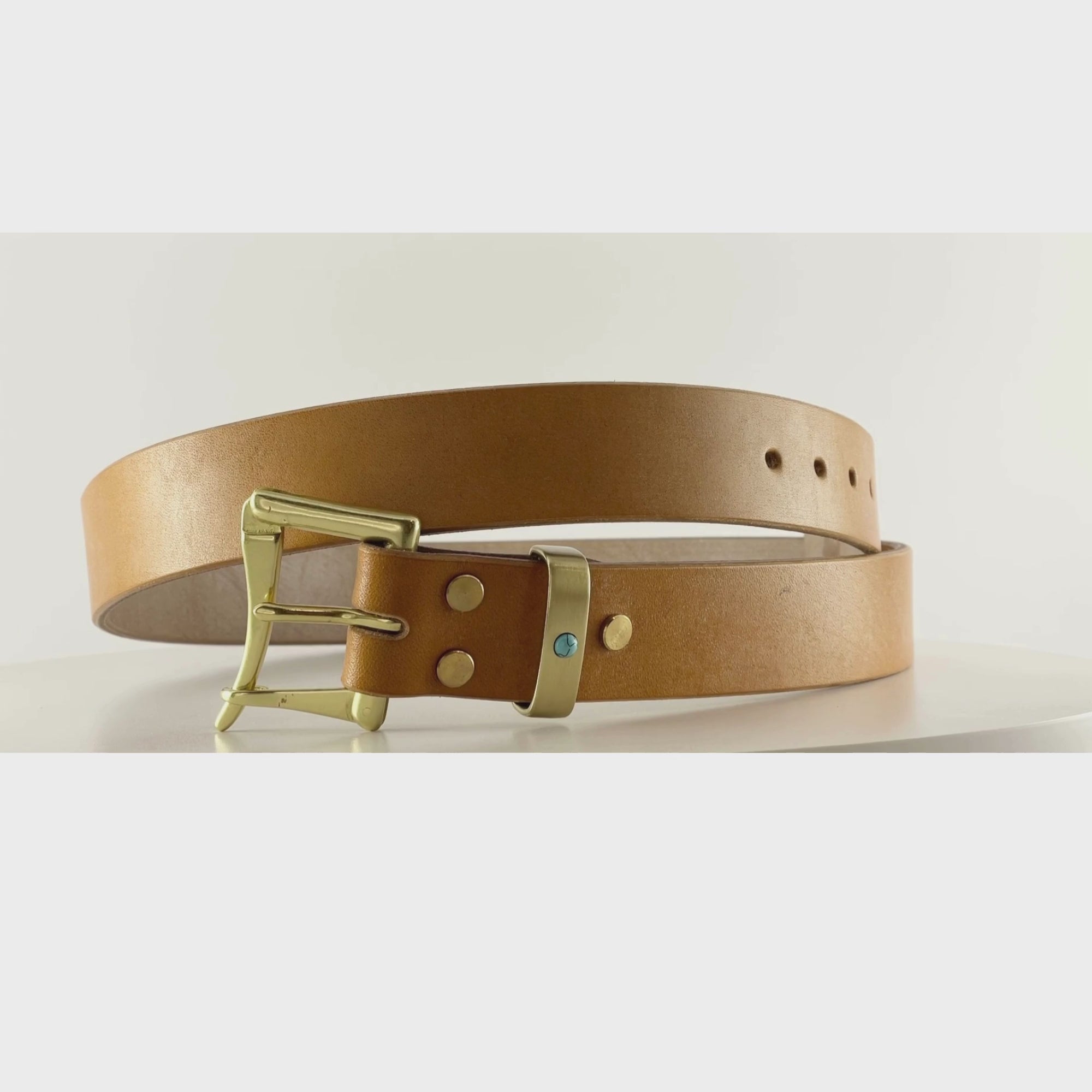 Video of an orange tan belt with a brass quick release buckle on a carousel
