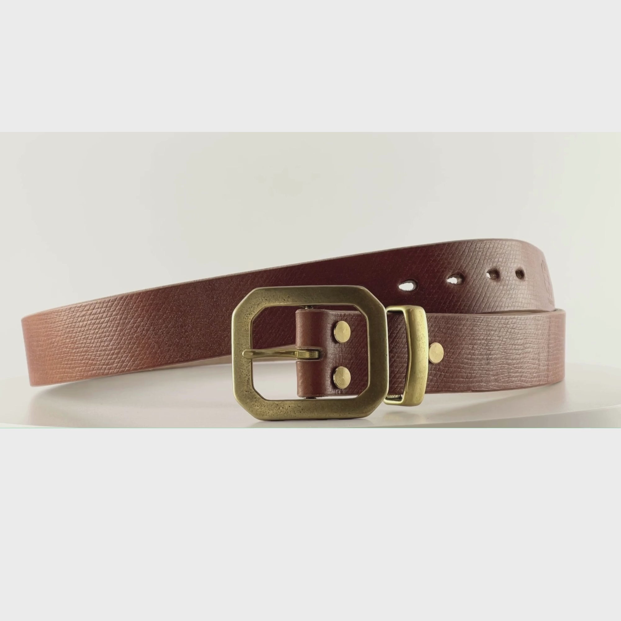 Video of a dark brown leather belt with an octagonal brass buckle on a carousel