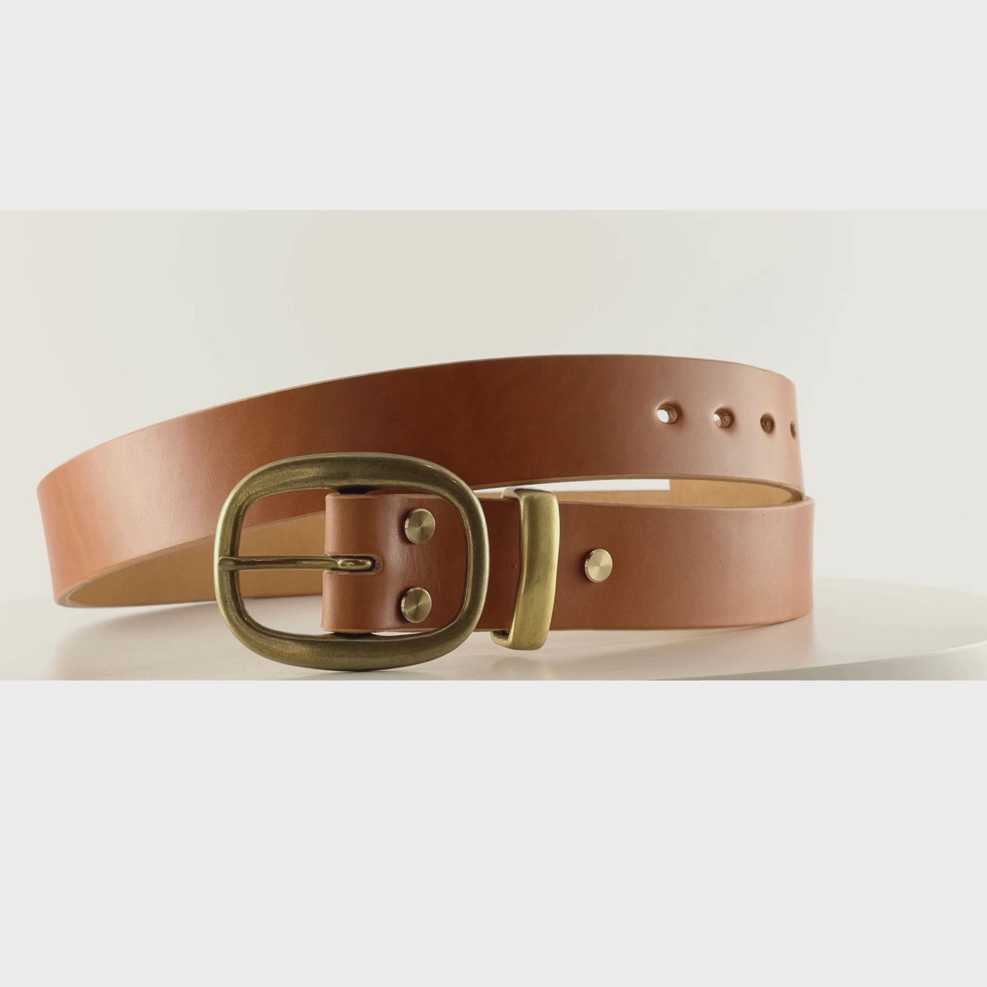 Video of a smooth tan leather belt with an oval brass buckle on a carousel