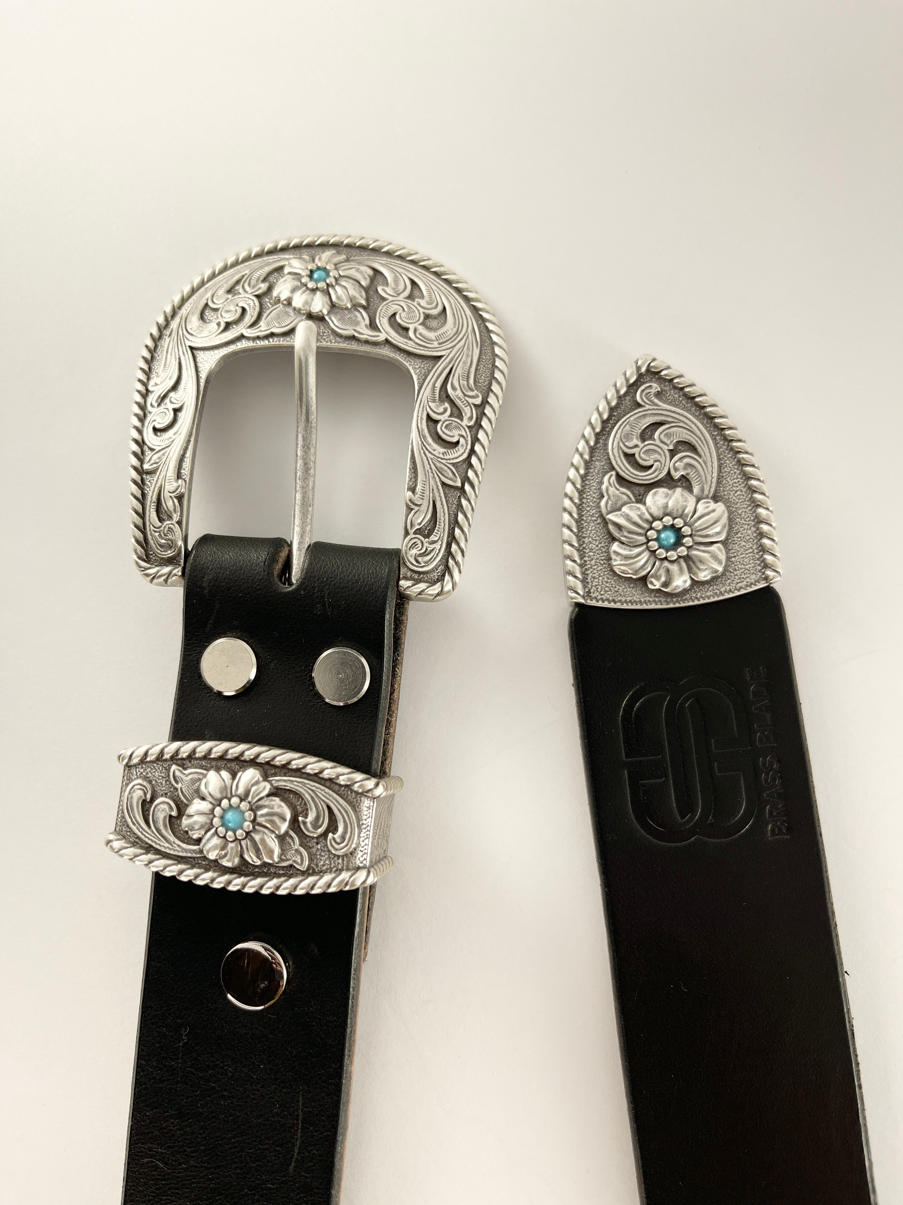 Black belt with silver floral buckle on a white background