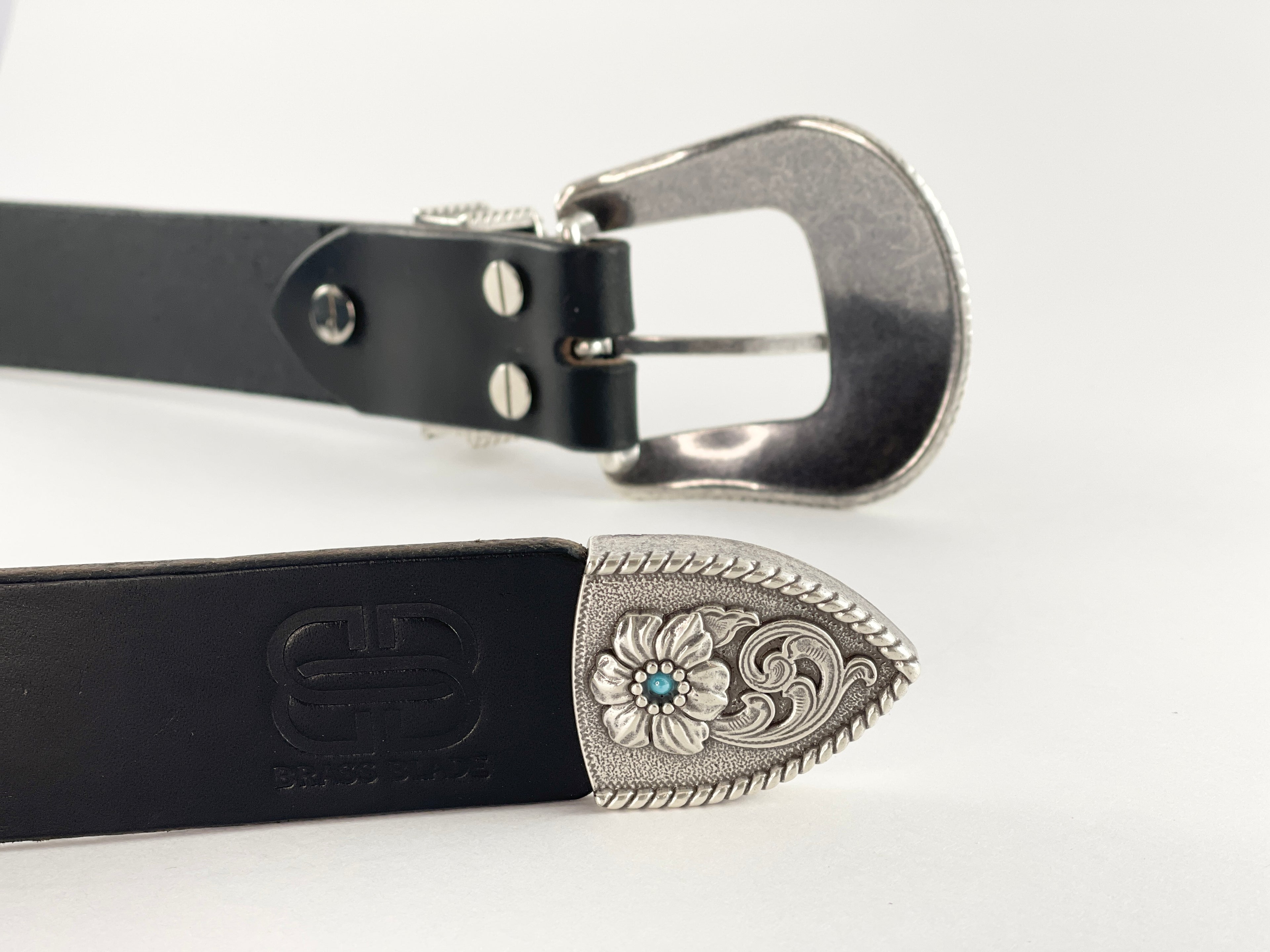 Black leather belt with silver floral buckle on a light gray background