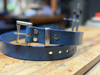 Blue leather belt with silver buckle on a wooden workbench