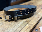 Black leather belt with silver buckle on a wooden surface