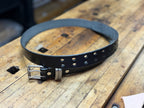 Black leather belt with silver buckle on a wooden surface