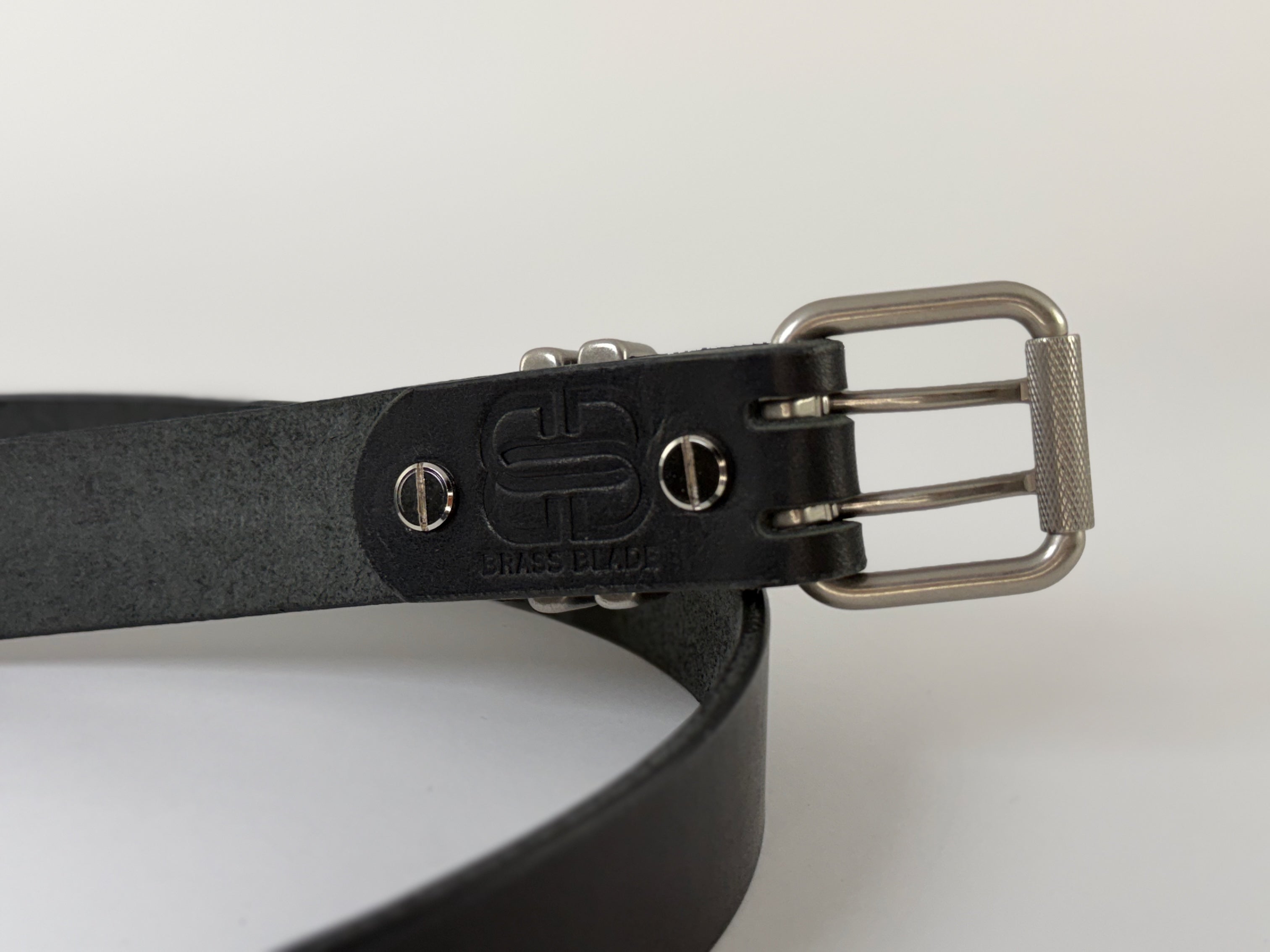 Back view of a black leather belt with silver buckle on a white background