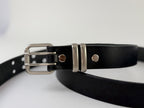 Black leather belt with silver buckle on a light gray background.  Picture is a closeup of the buckle, Chicago screws and double silver belt keepers.