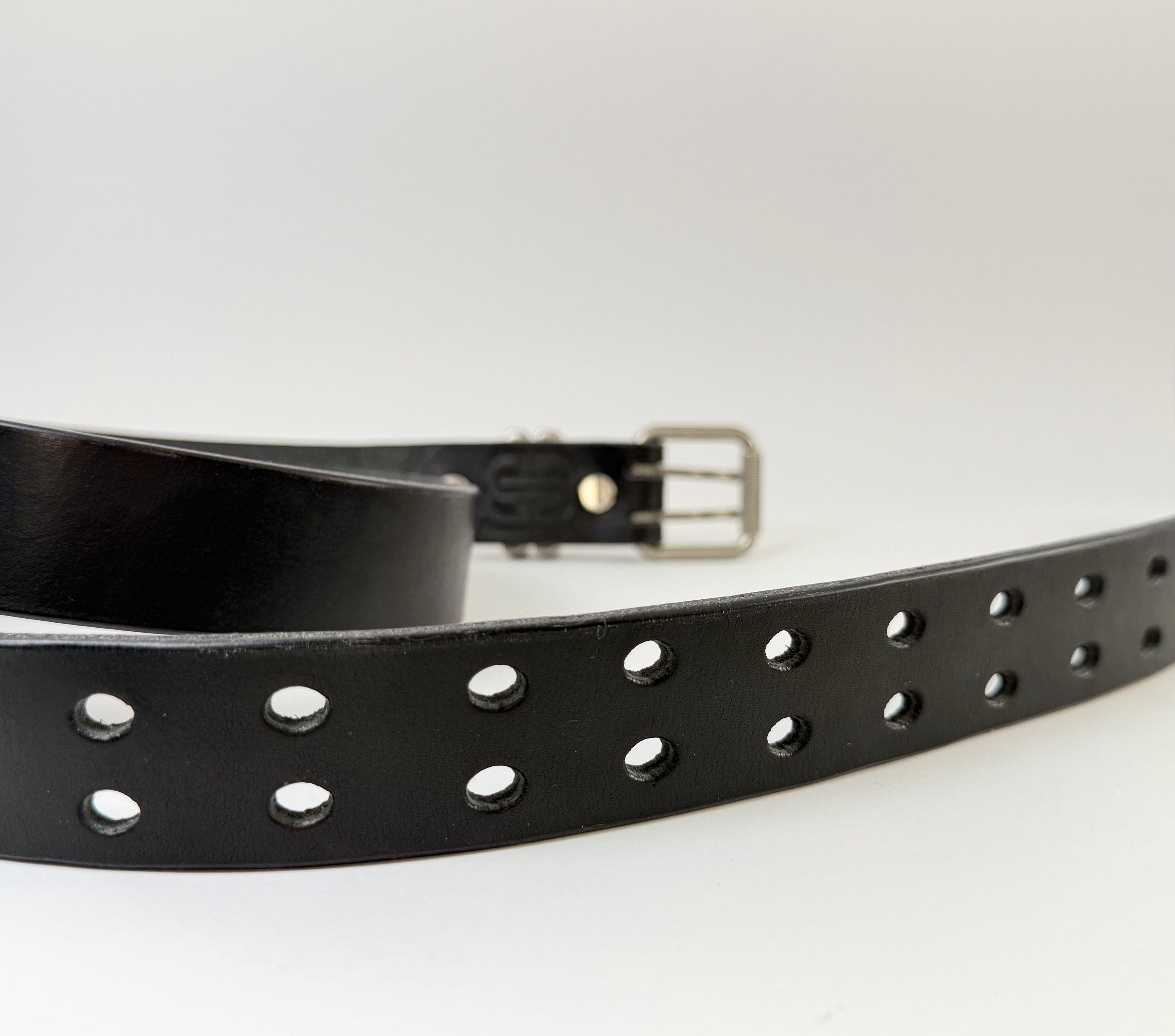 Black leather belt with closeup of belt holes on a white background