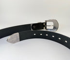 The back side of a black western cowboy belt with silver buckle and keeper on a light gray background