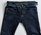Dark blue jeans with a blue indigo-dyed belt on a light gray background