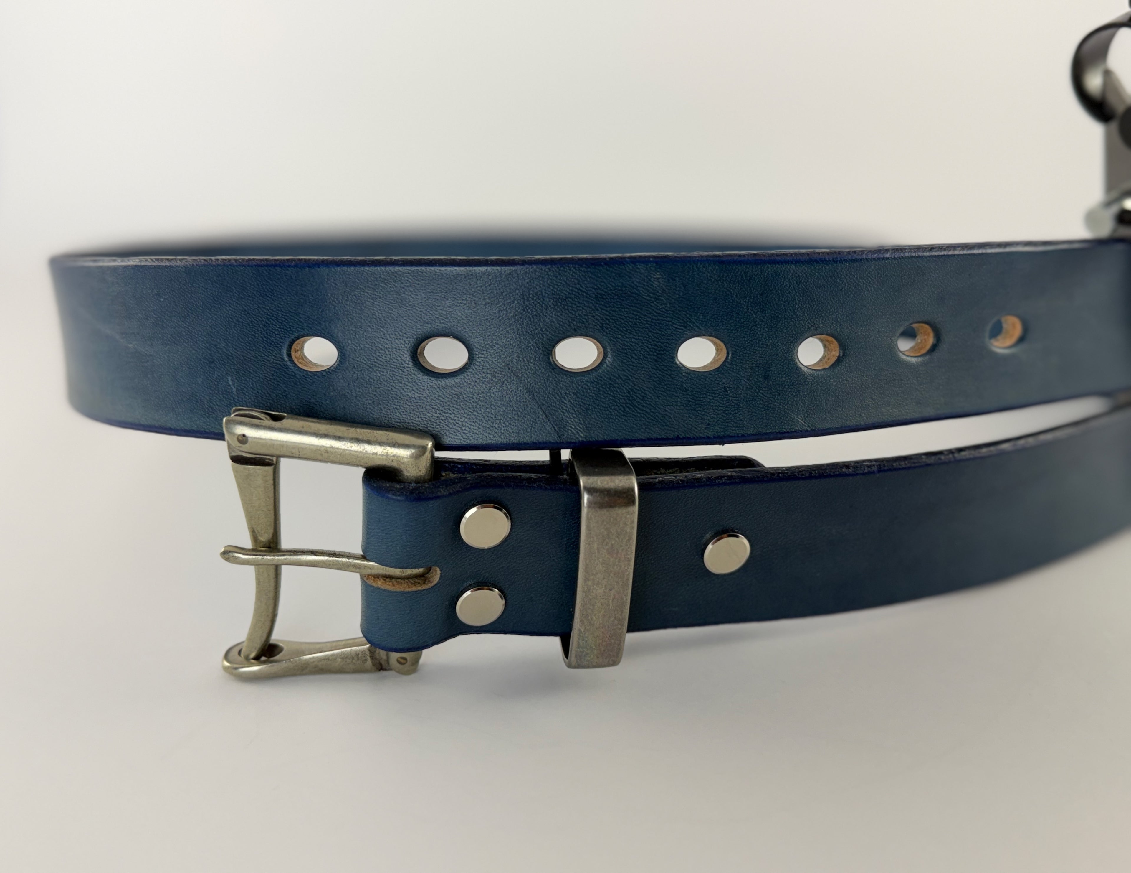 Blue leather belt with silver buckle on a white background