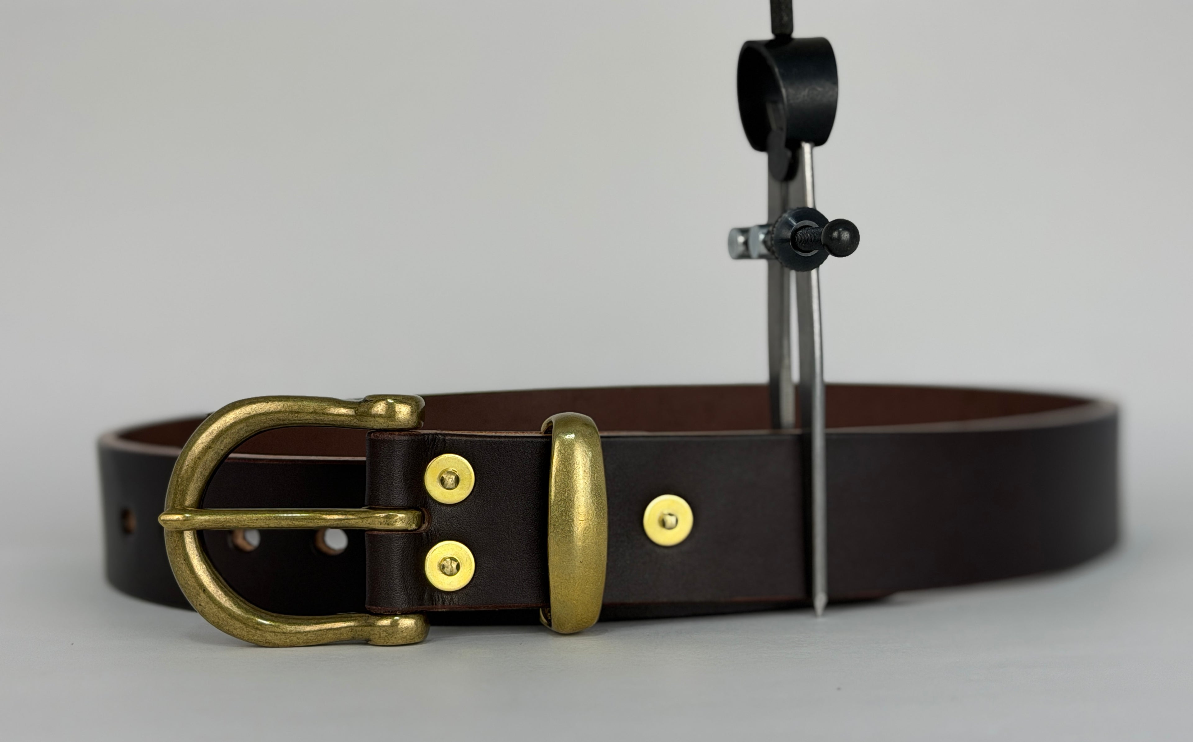 Picture of a brown leather belt with a close up of brass buckle, keeper and rivets.