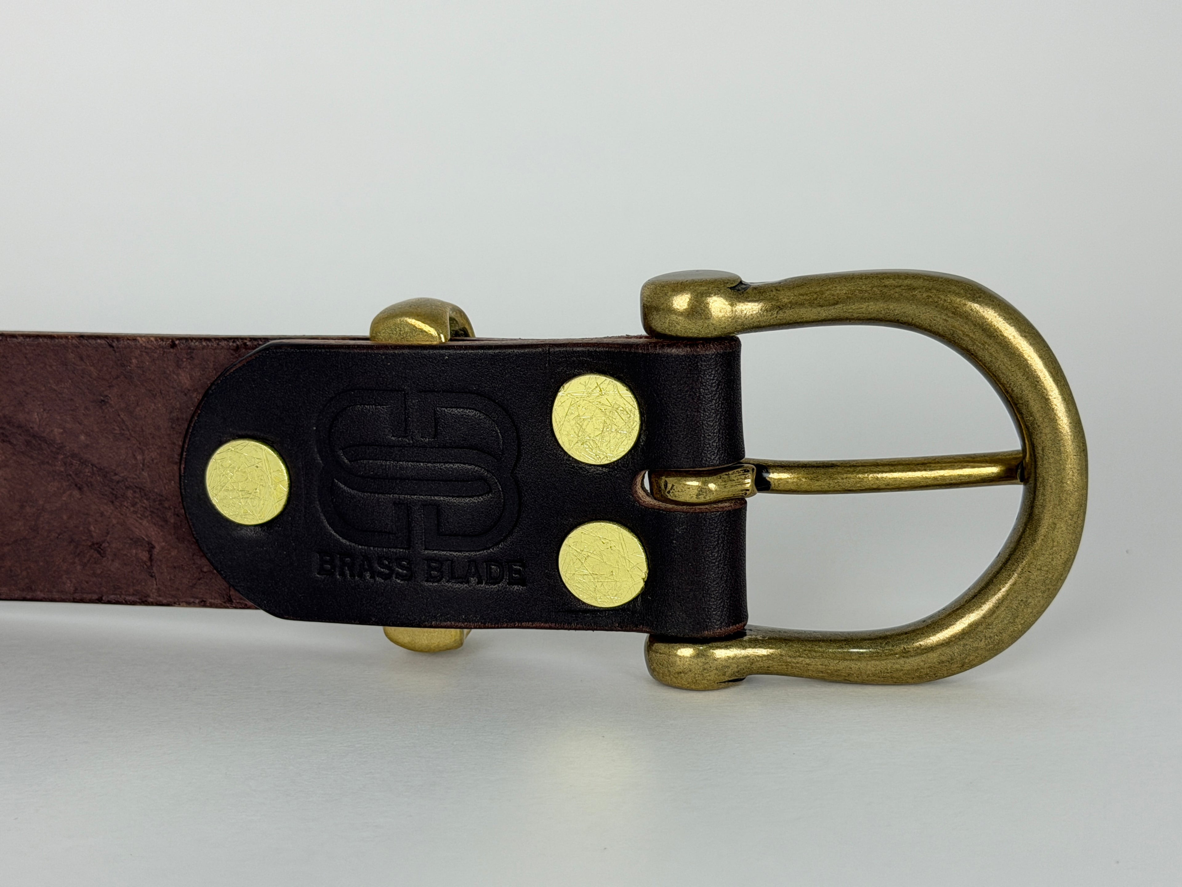 Picture of the back of a brown leather belt showing brass rivets and brass keeper and buckle.
