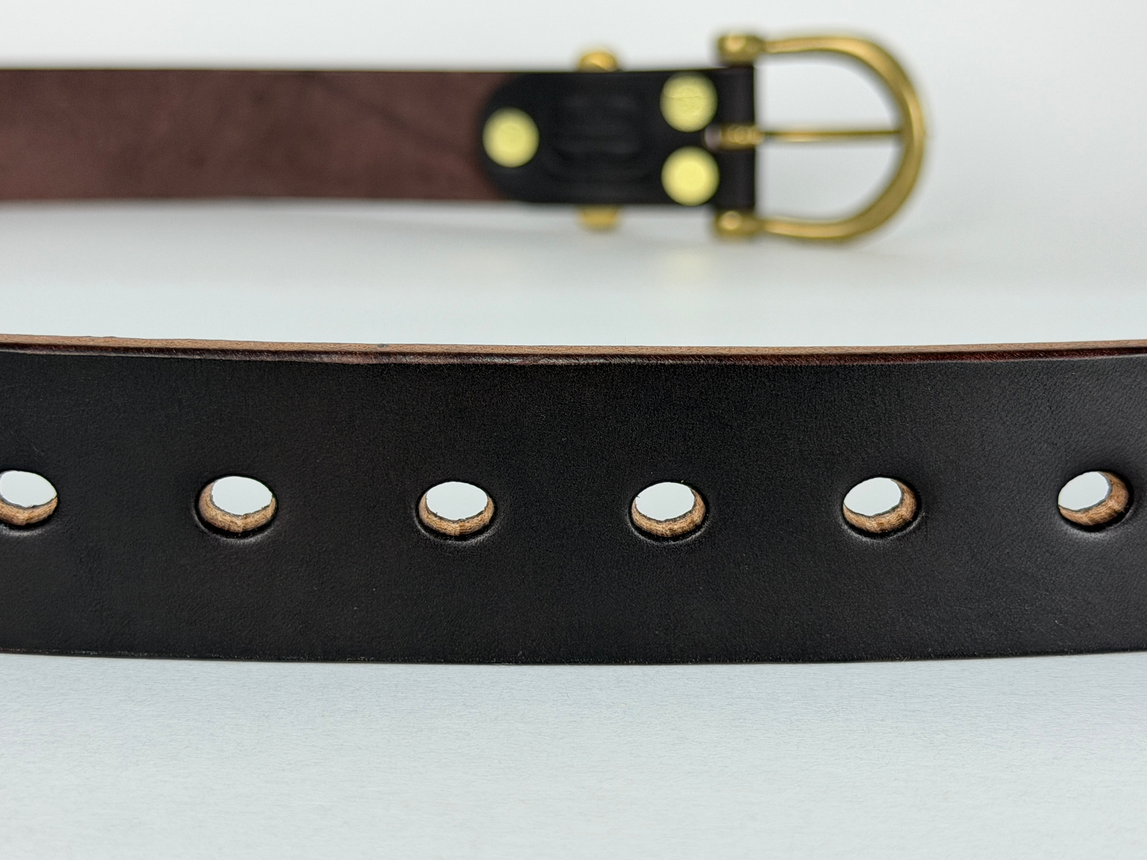 Close up picture of a leather belt showing oval-shaped belt holes.