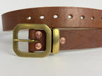 Closeup from view of a brown leather belt with a brass buckle, keeper and copper rivets on a white background.  The 7 punched holes are also in focus.