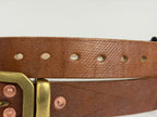 Closeup view of the cross hatch pattern on a brown leather belt highlighting the 7 punched holes on the belt.