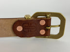 Closeup view of the back of a brown leather belt with a brass buckle, keeper and copper rivets on a white background.