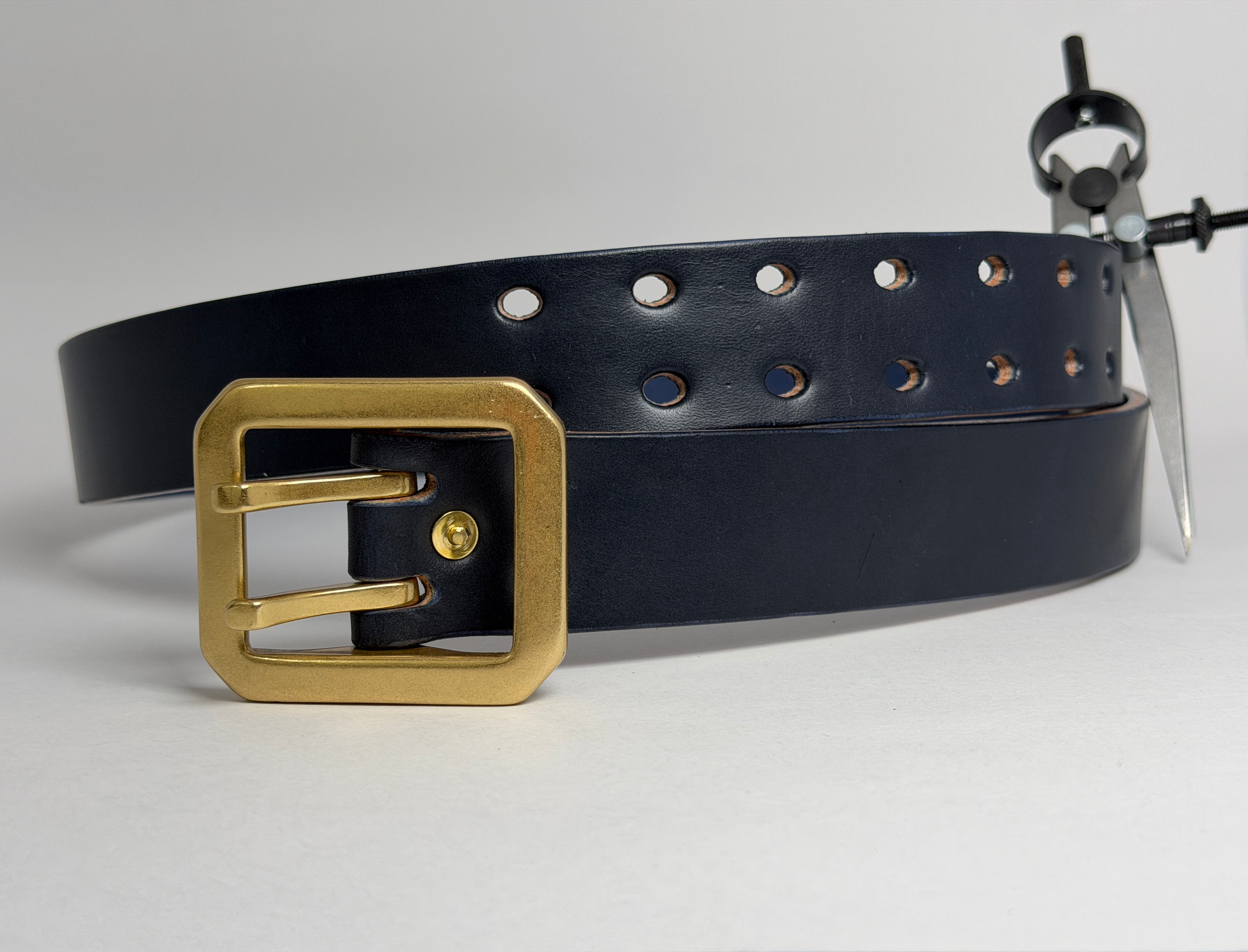 Front view of a Navy leather belt with a brass buckle on a light gray background