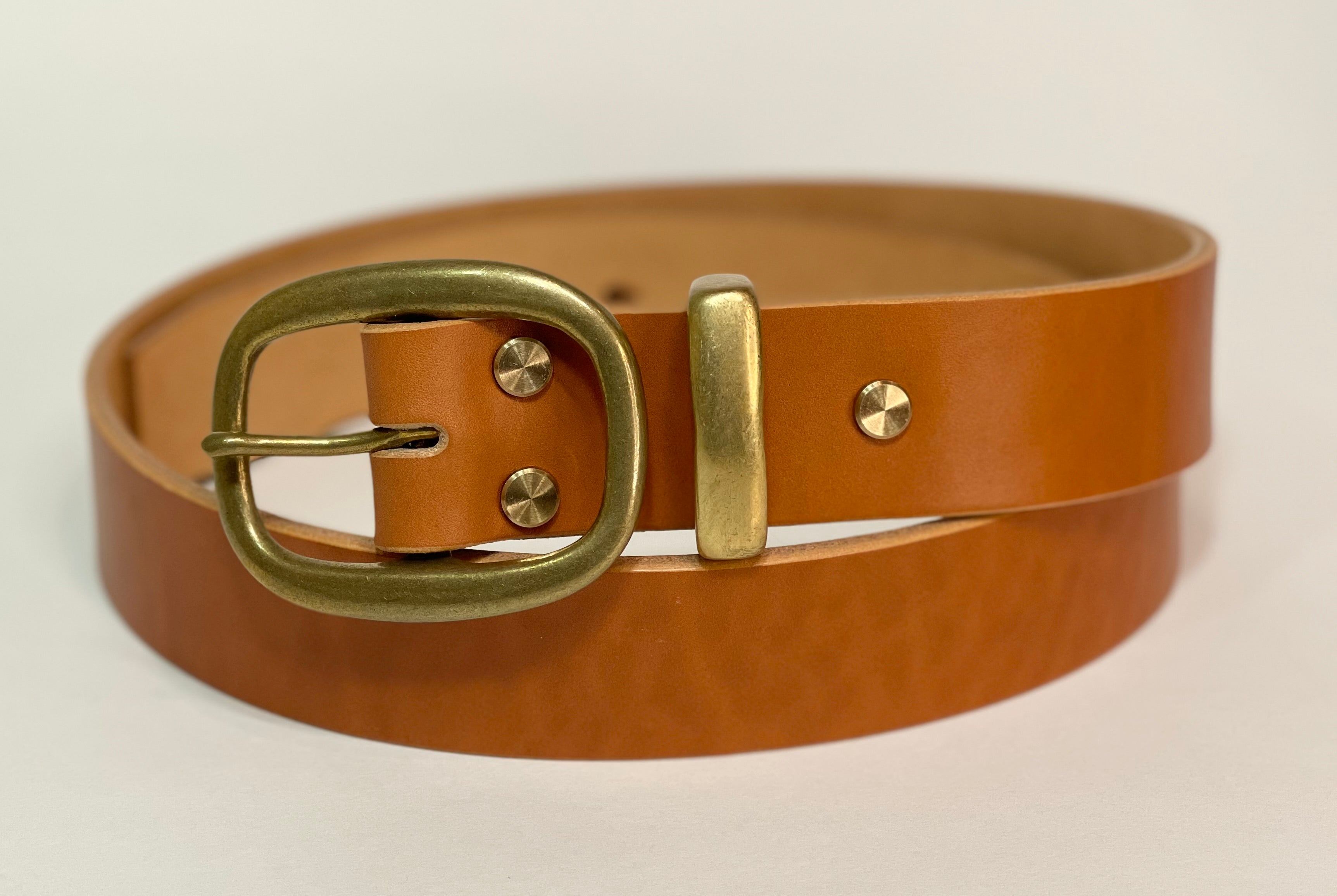 Brown leather belt with a brass buckle on a beige background