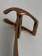 A close-up top view of a copper horseshoe buckle, shown against a plain light gray background.