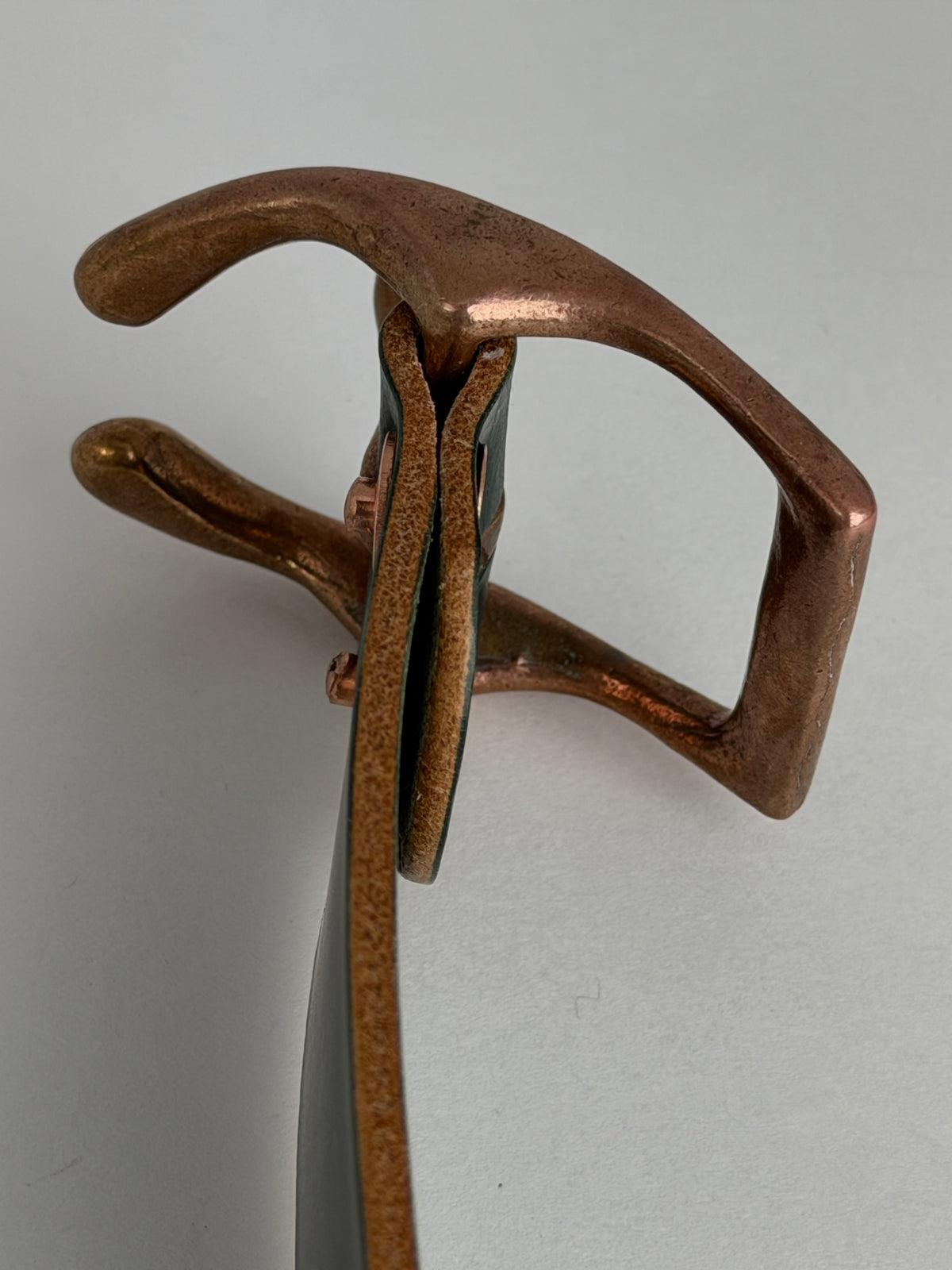 A close-up top view of a copper horseshoe buckle, shown against a plain light gray background.