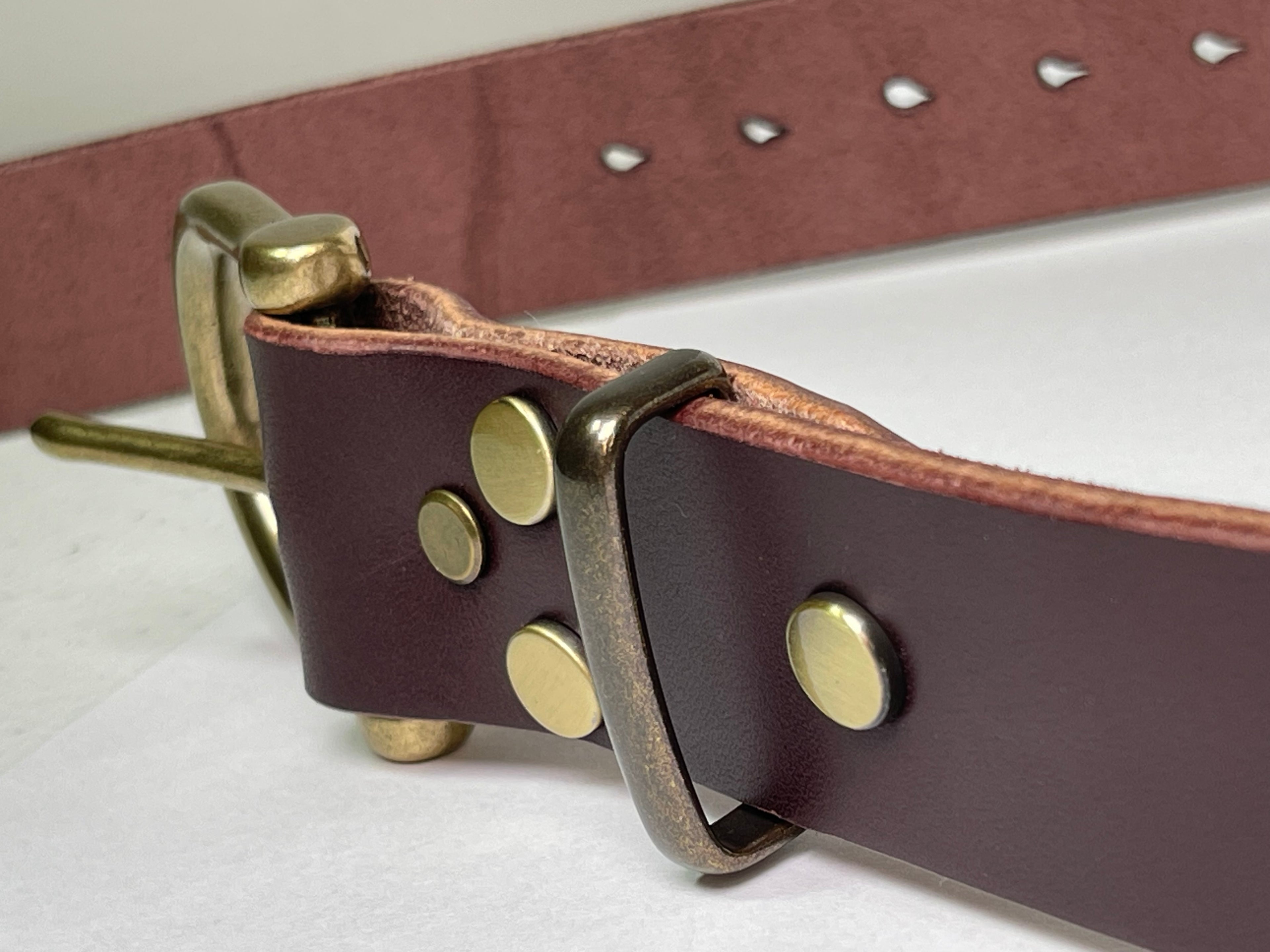 Brown leather belt with brass buckle on a white background