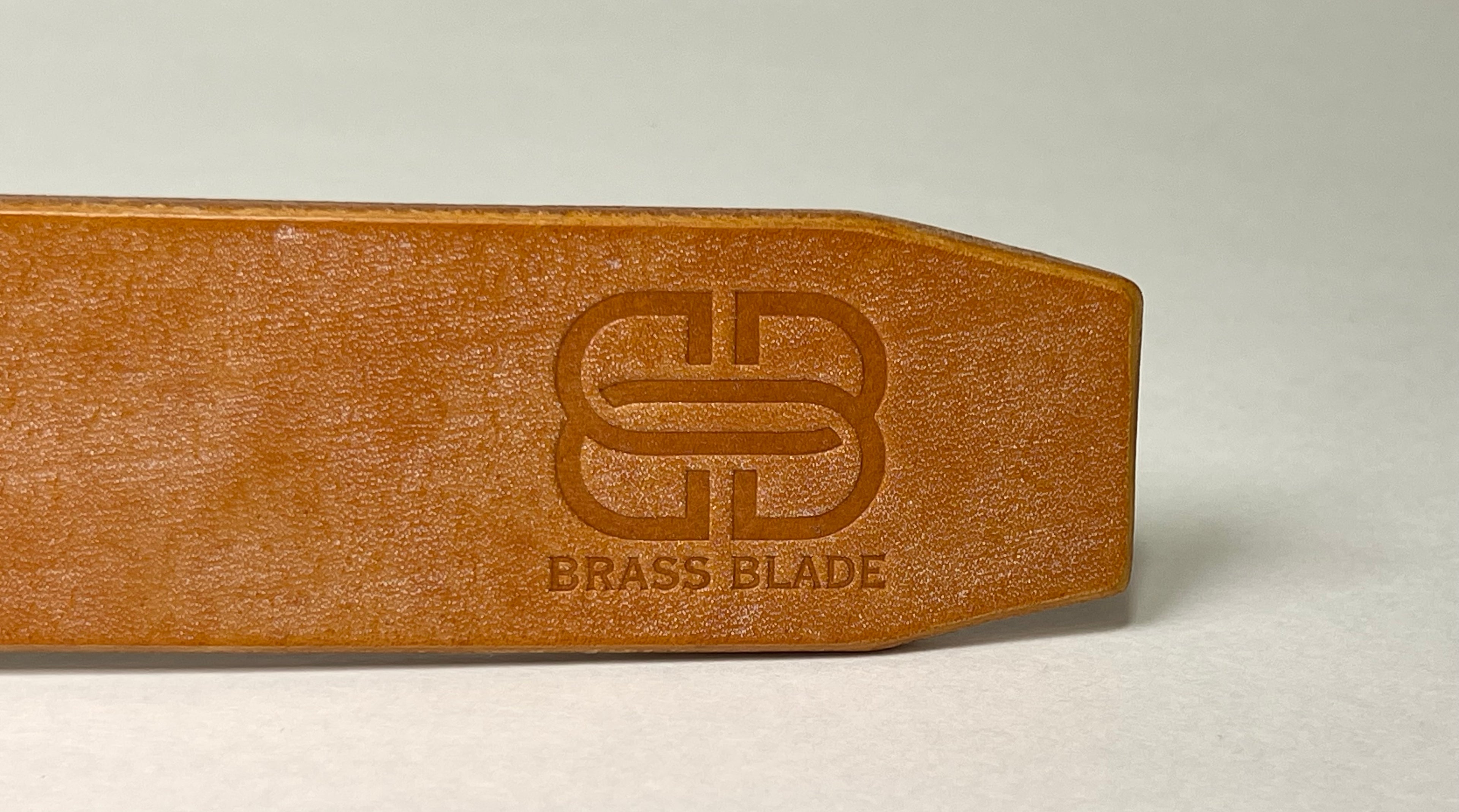 Brown leather belt end with 'Brass Blade' branding on a white background