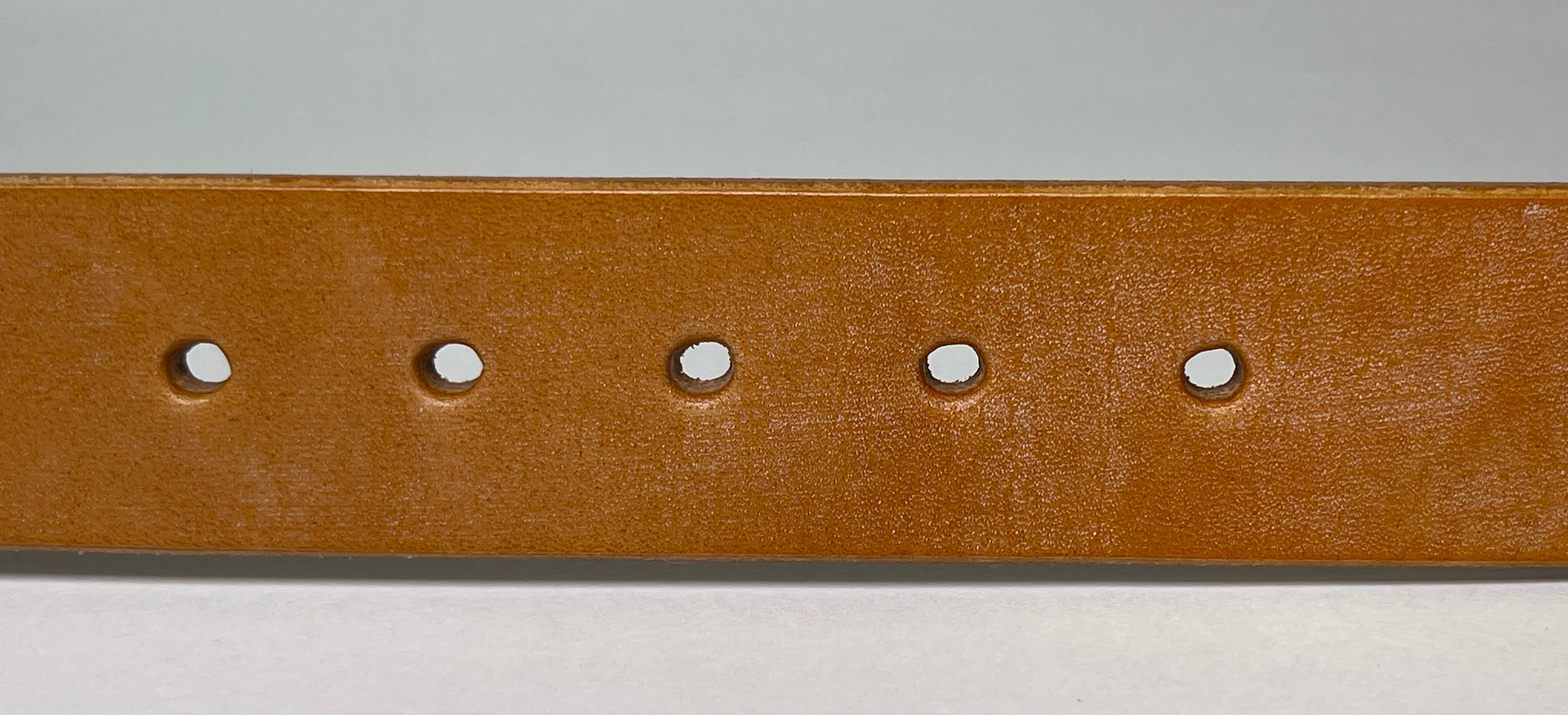 Brown leather belt with five holes on a gray background