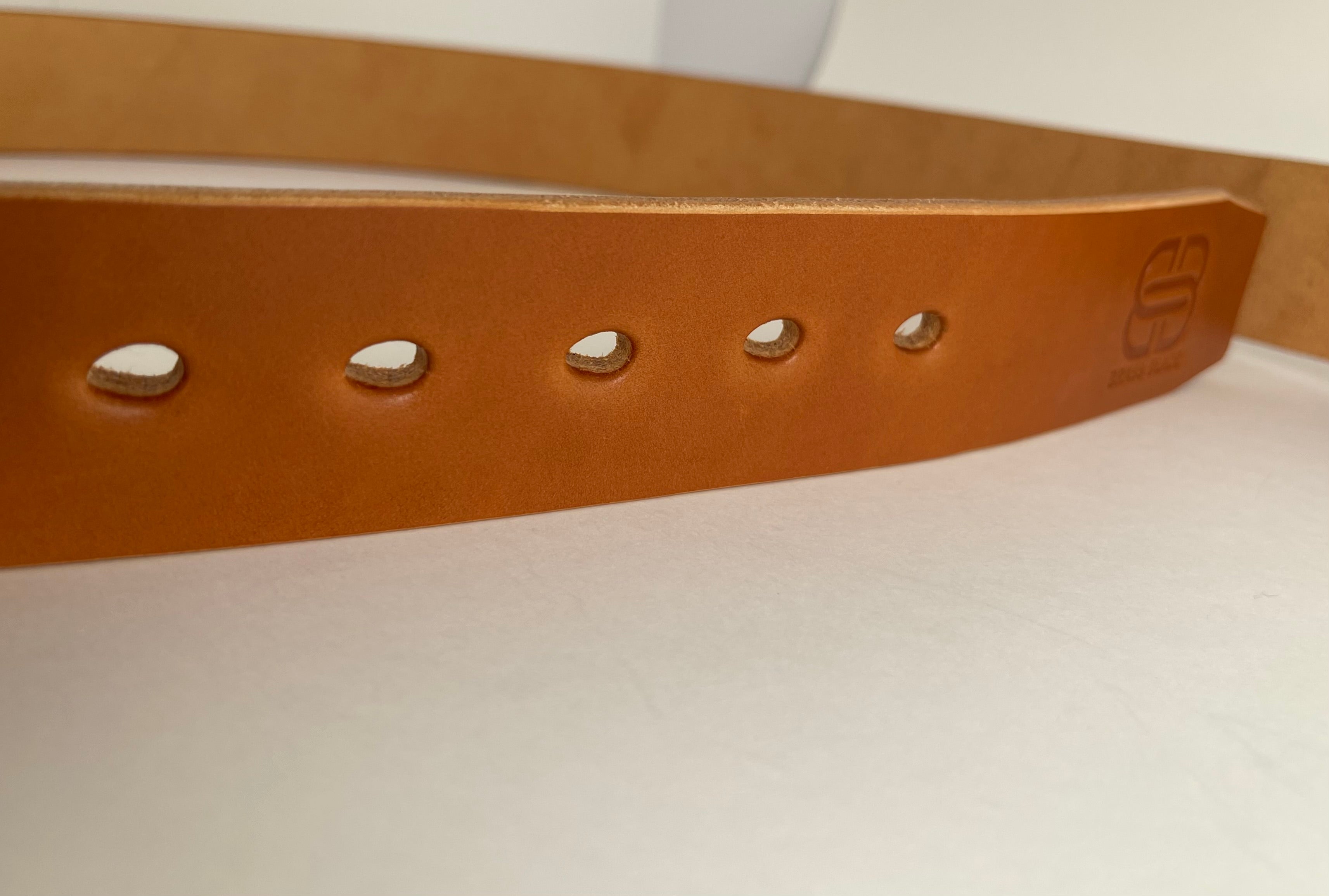 Brown leather belt with teardrop shaped holes on a white background