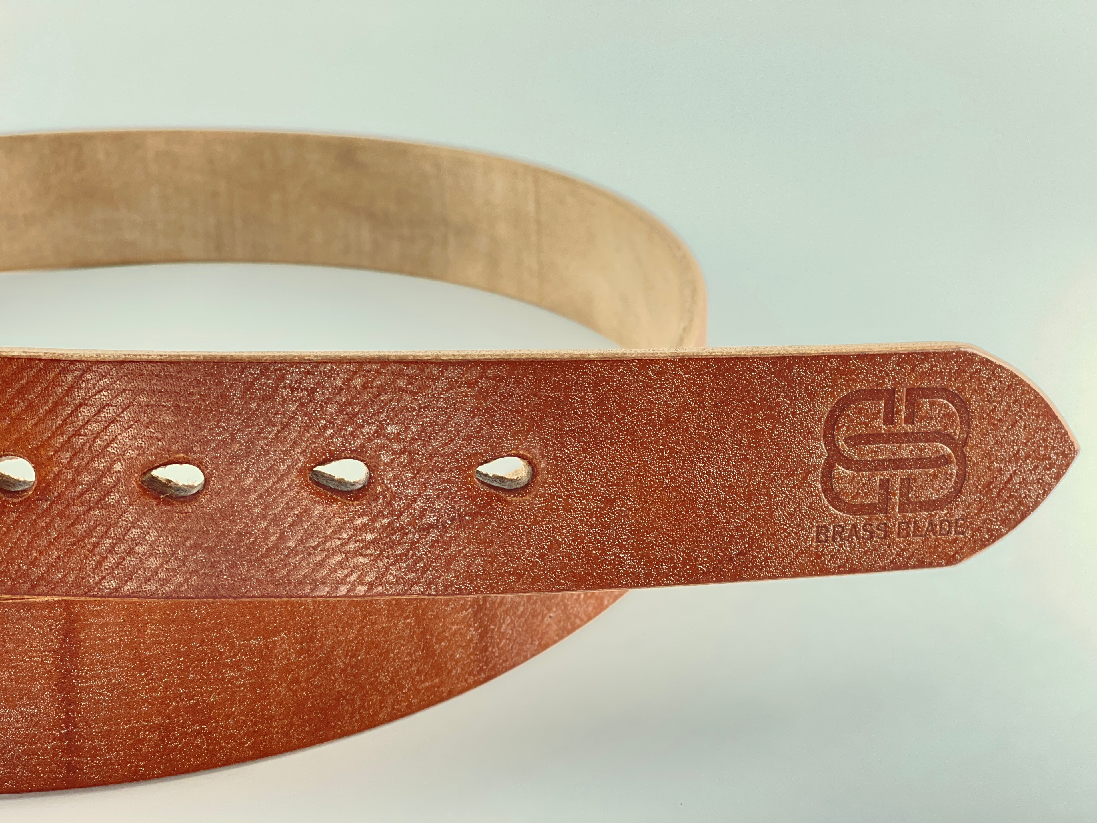 Brown leather belt with gold buckle on a light gray background with the words "Brass Blade" stamped on it