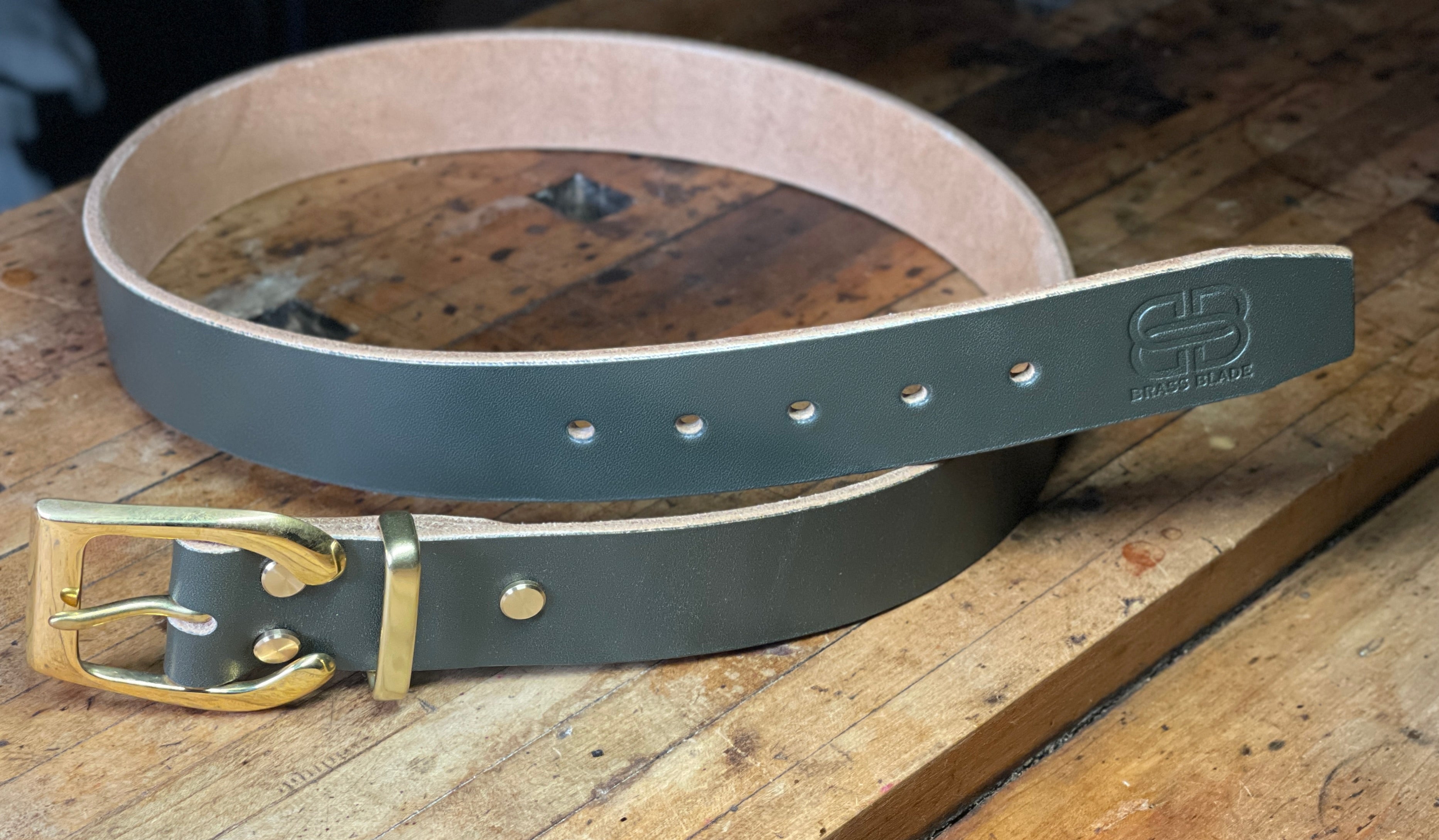 Dark green leather belt with gold buckle on a wooden surface