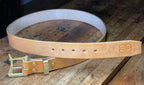 Tan leather belt with gold buckle on a wooden surface