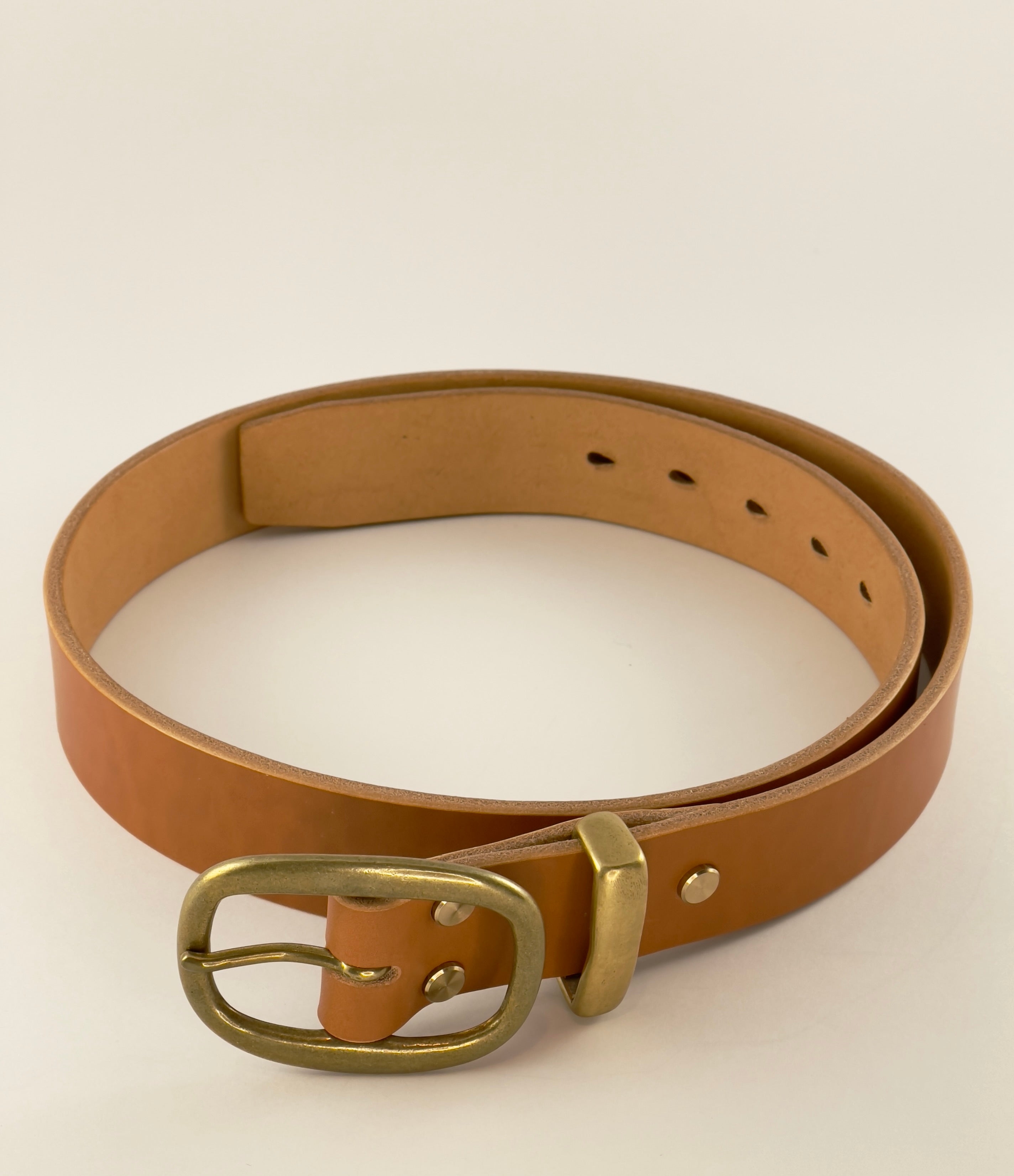 Brown leather belt with a brass buckle on a beige background