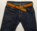 Dark blue jeans with a brown belt and brass buckle on a white background