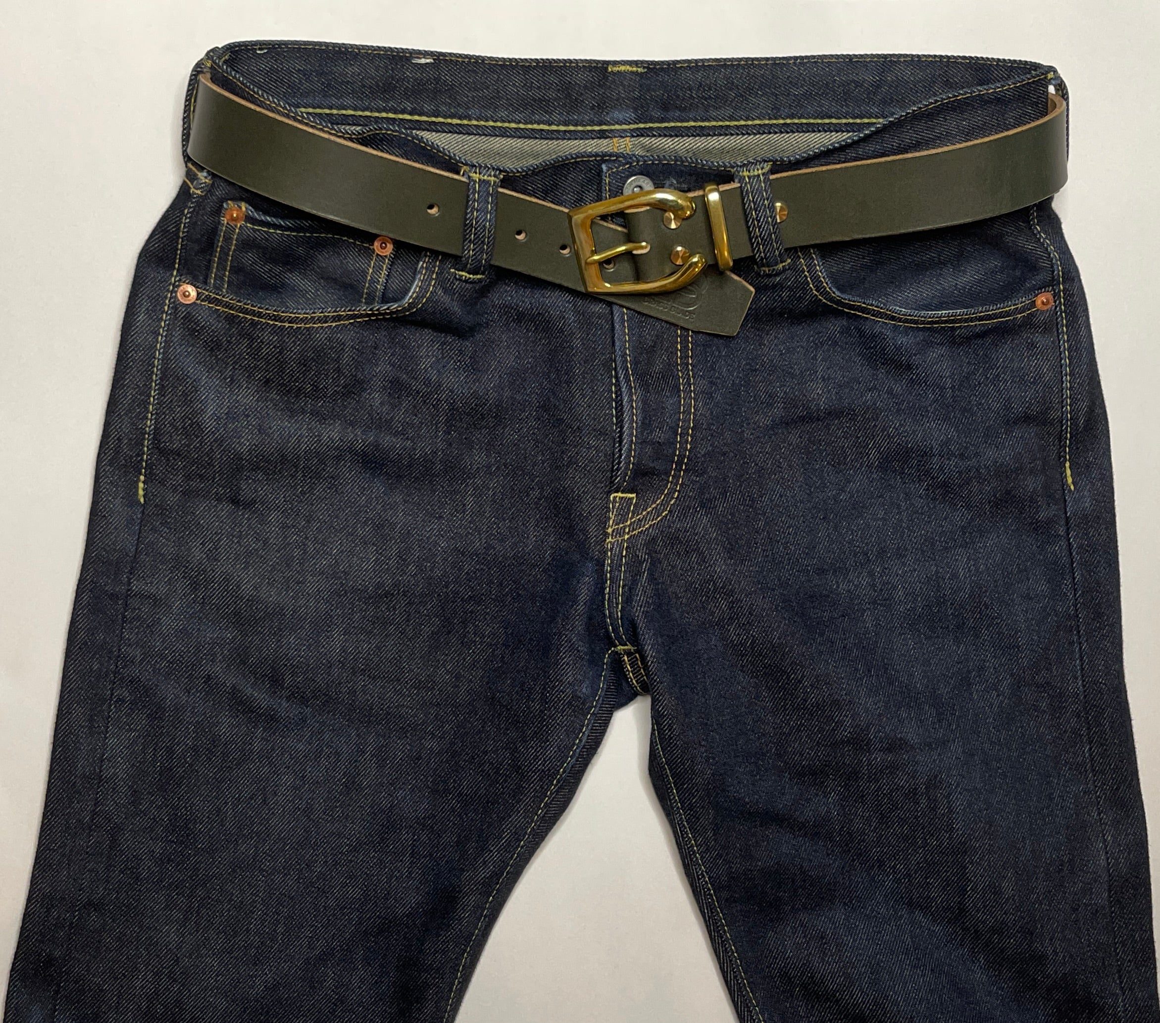 Dark blue jeans with a dark green belt and gold buckle on a light gray background