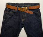 Dark blue jeans with a brown belt and gold buckle on a white background