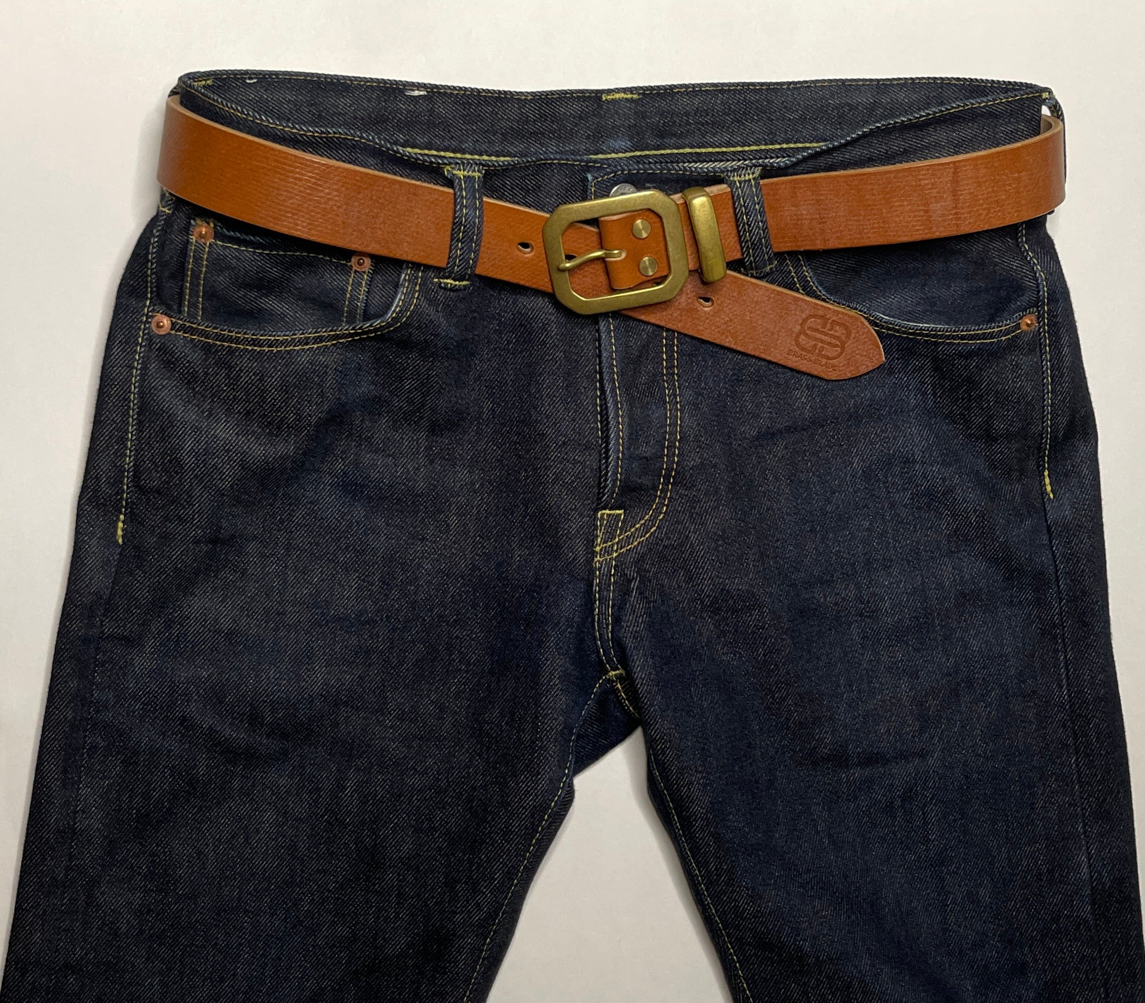 Dark blue jeans with a brown belt and gold buckle on a white background