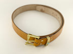 Tan leather belt with a gold buckle on a light beige background