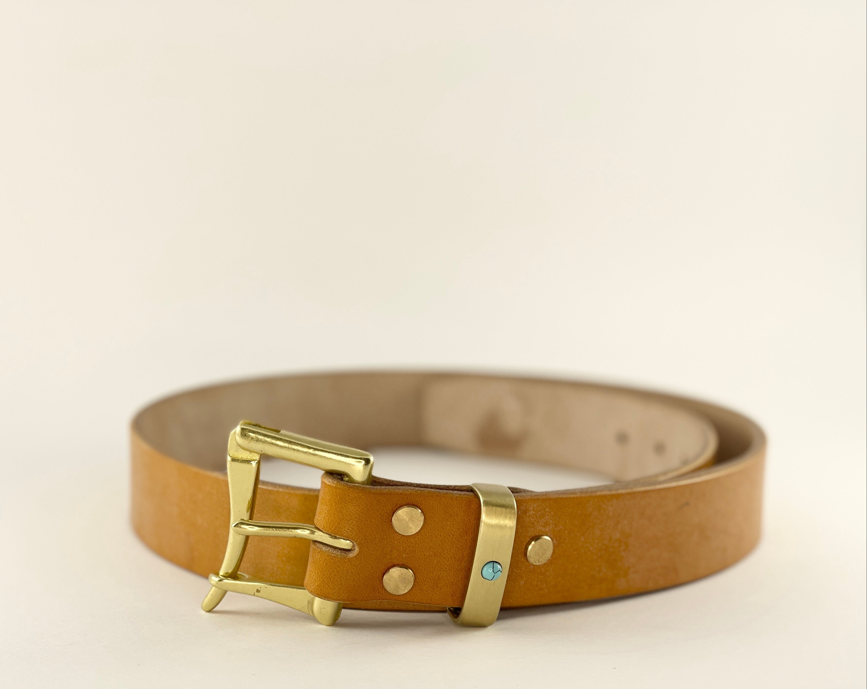 Brown leather belt with a gold buckle on a beige background