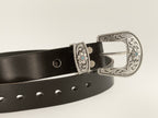 Black belt with a silver floral buckle on a light gray background