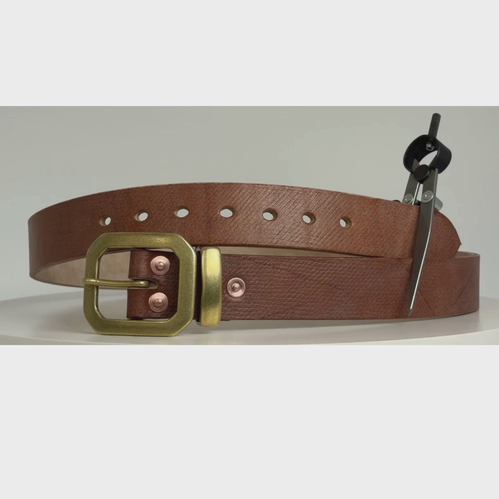 Video of a brown leather belt with brass octagonal-shaped buckle, keeper and brass rivets.  The video shows this belt rotating 360 degrees on a carousel.