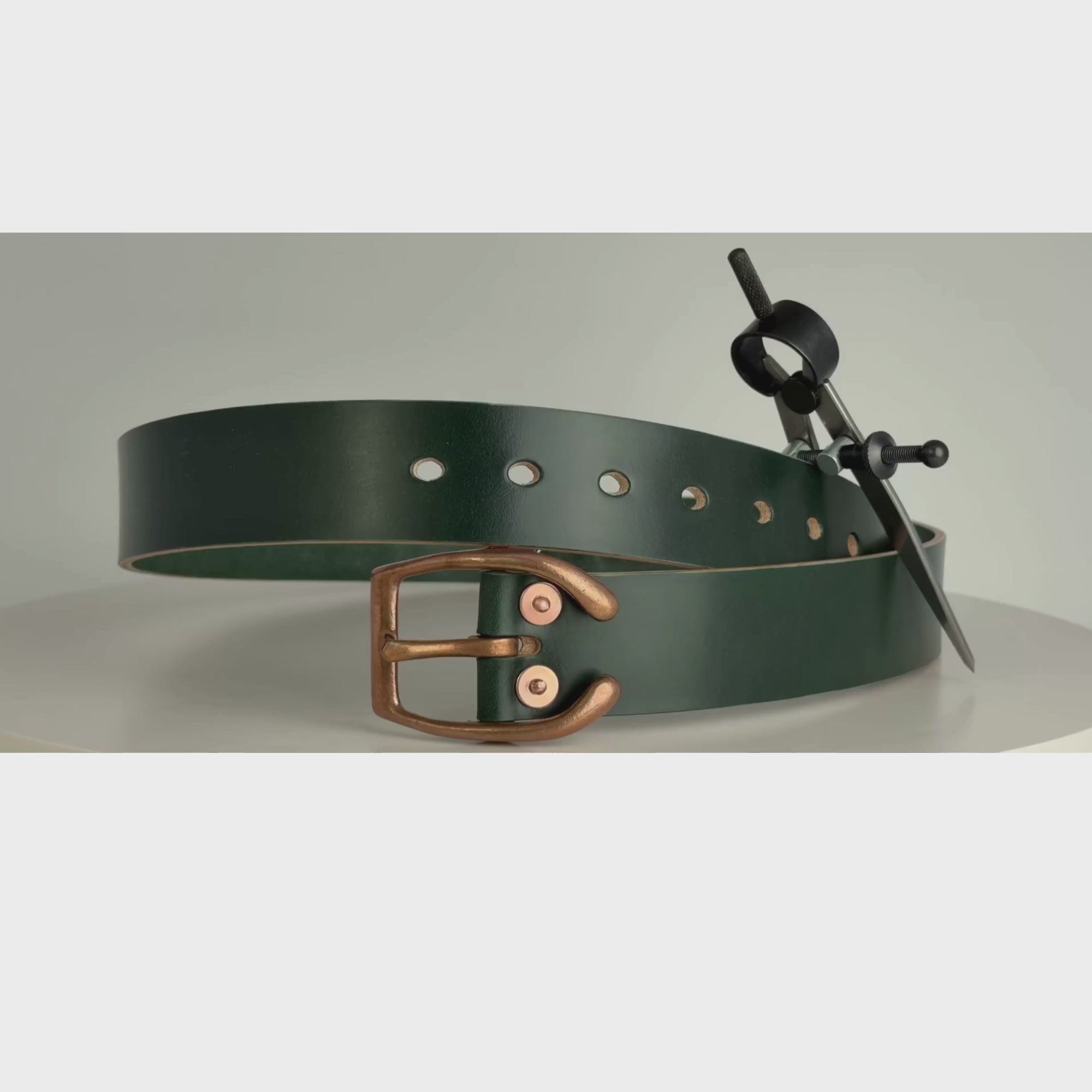 This is a video of a belt rotating on a carousel.  This belt is made from dark green leather, with a copper horseshoe buckle and copper rivets.